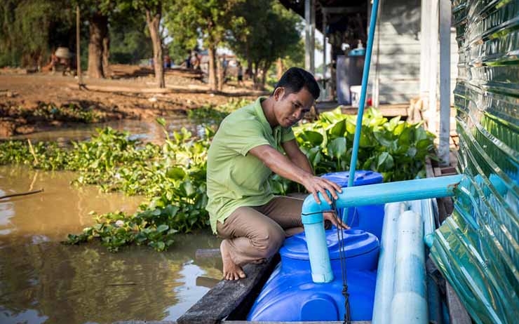 Un cambodgien remplie des citernes d'eau