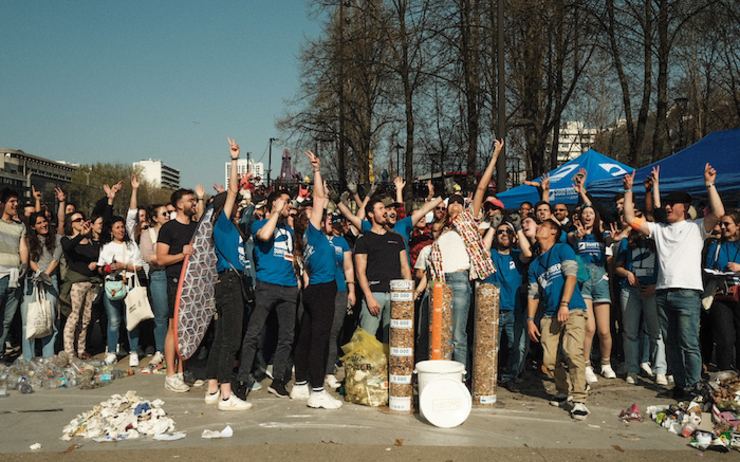 Un groupe de personnes lèvent les bras devant des boites pleines de mégots collectés