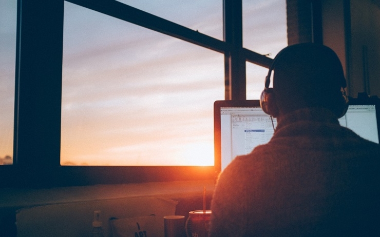 un homme télétravaille sur ordinateur avec lever de soleil simon-abrams-unsplash