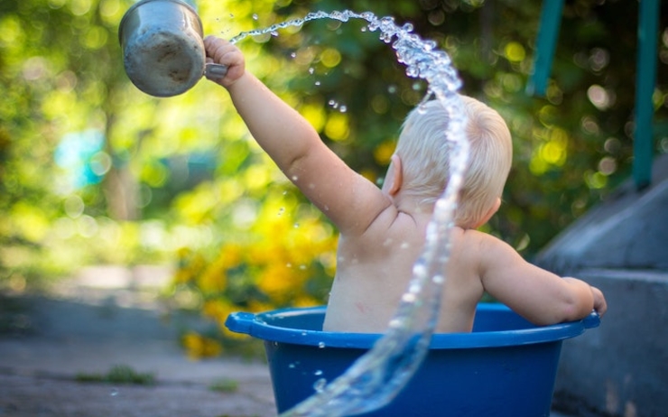 Un petit garçon s'asperge d'eau