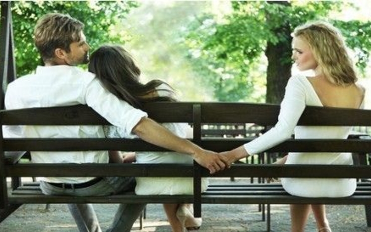 Un couple infidèle se donne la main sur un banc 