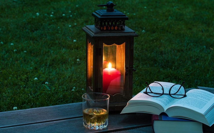 Une lanterne brille sur une petite table près d'un livre 
