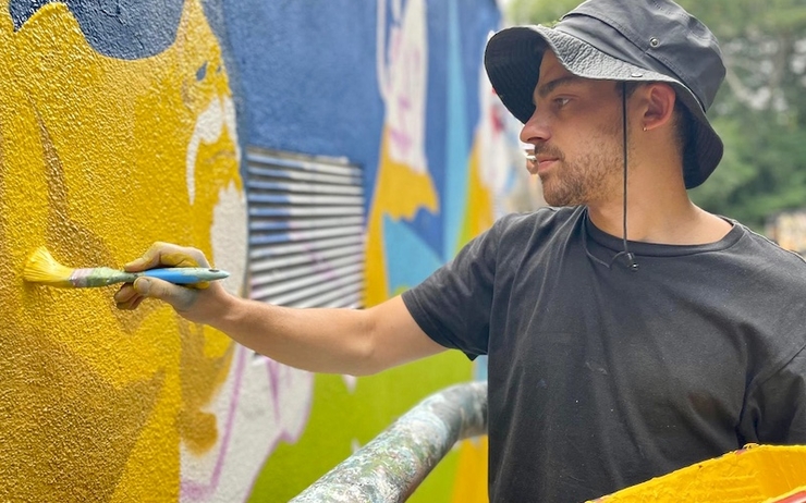 un homme avec un chapeau en train de peindre sur un mur 