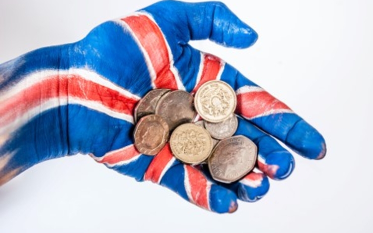 Une main peinte tient des pièces de monnaie britannique