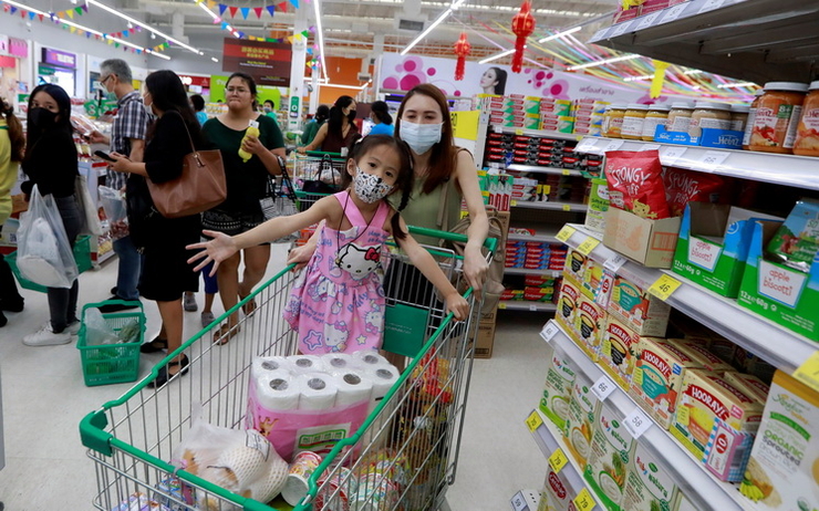 Une famille pousse une cadie dans le supermarché en Thailande 