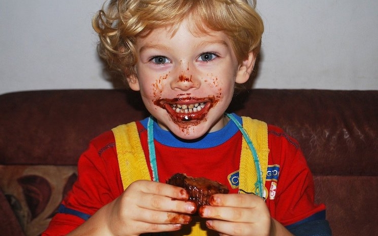 Petit garçon bouche pleine de chocolat