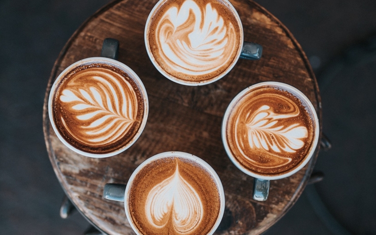 Quatre cafés latte sont posés sur une table 