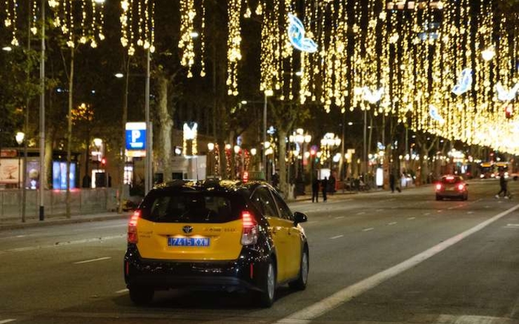 un taxi en train de rouler la nuit sur une avenue avec des décorations de Noel à Valencia