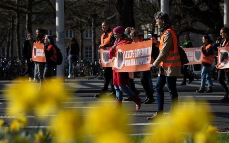 Militants de Letzte Generation défilant avec une banderole "Vor den Kipppunkten"