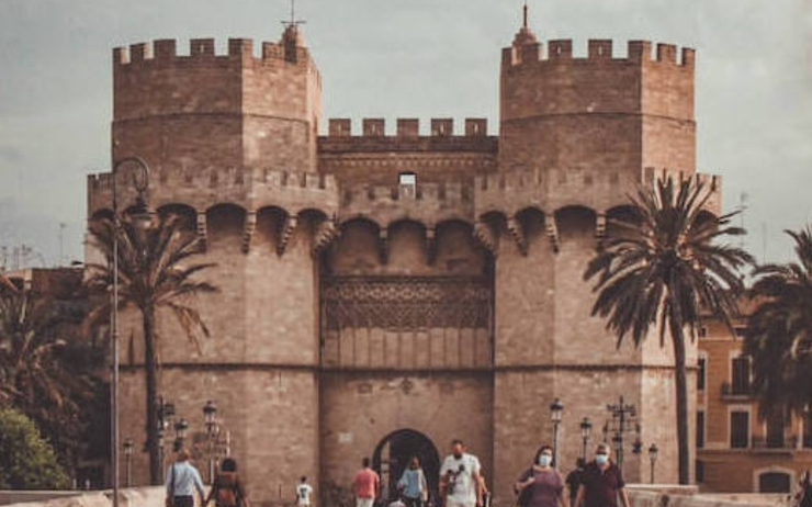 des piétons en train de marcher devant les portes de la ville de Valencia pendant les Fallas 2023