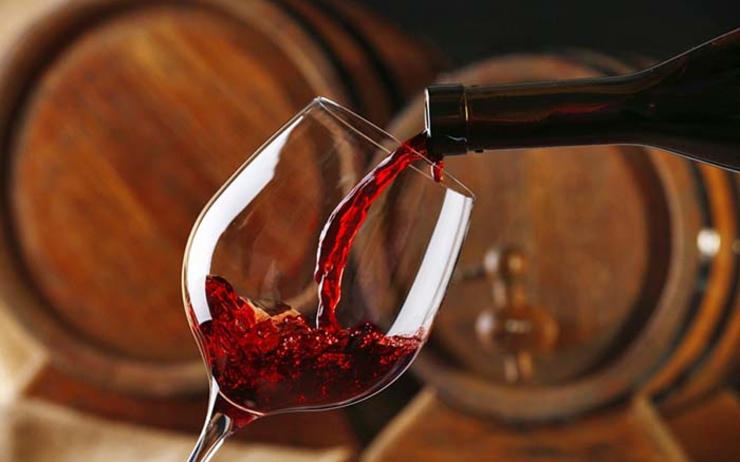 Un verre de vin se remplit de vin rouge dans une cave de tonneaux en Roumanie